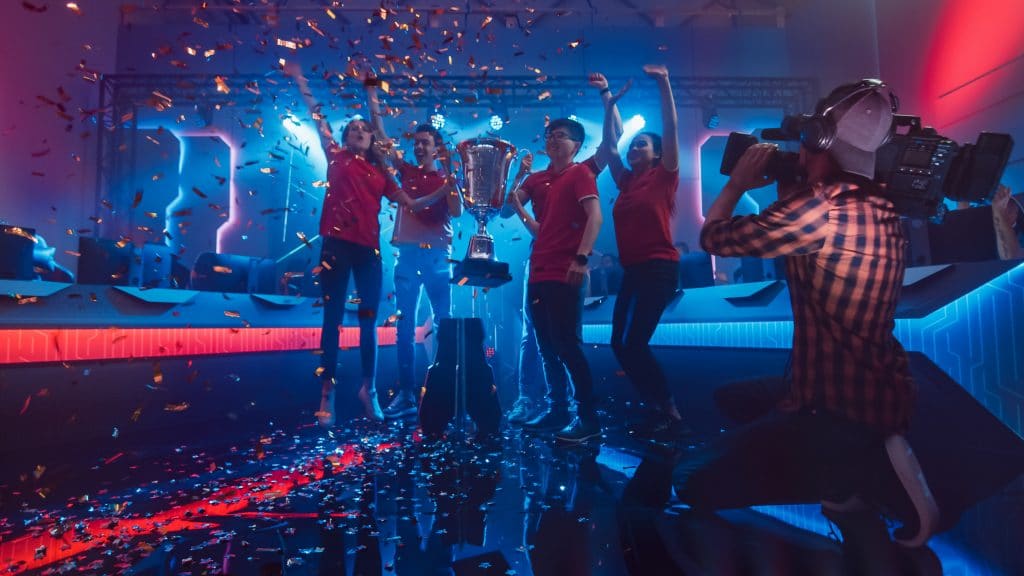 Diverse Esport Team Winner of the Video Games Tournament Celebrates Victory Cheering and Holding Trophy in Big Championship Arena. Pro Computer Gaming Event with Player, Gamers Having Fun.