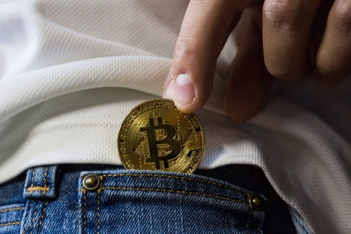 man putting bitcoin in pocket