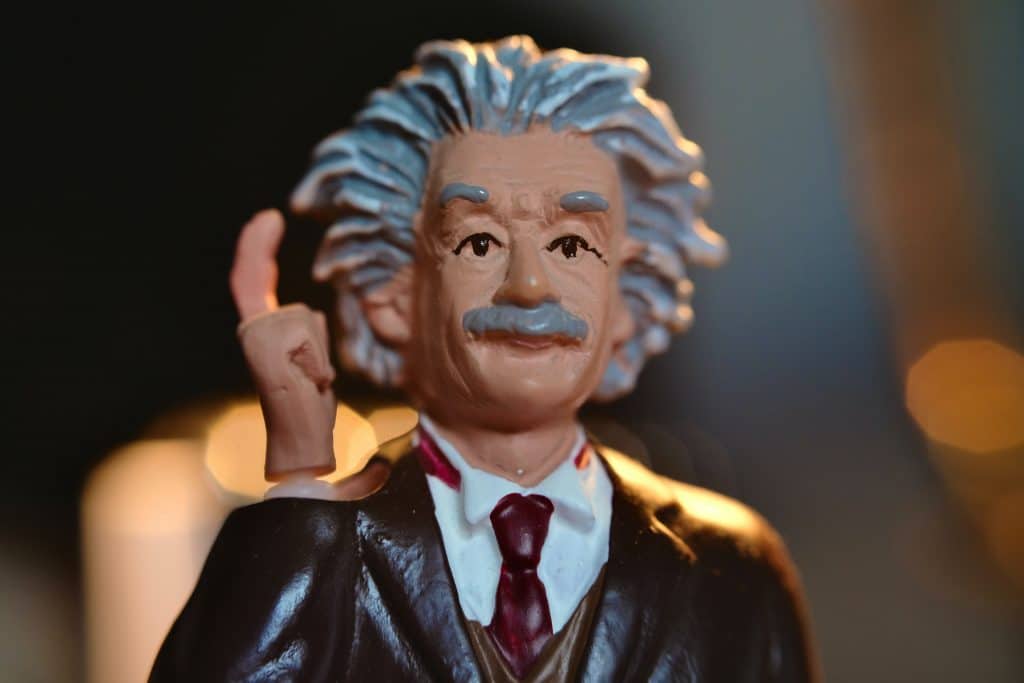 Crude figurine of Albert Einstein  in focus with right hand and finger raised