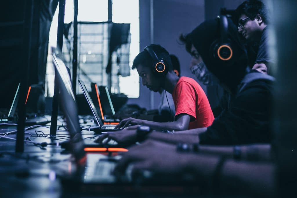 Side profile of several gamers playing PCs on large desk area in sepia tones