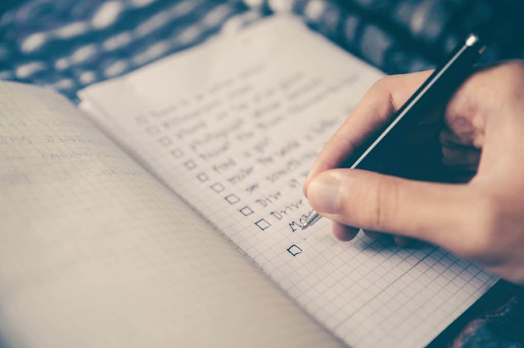 person writing check box notes in a note pad with soft focus